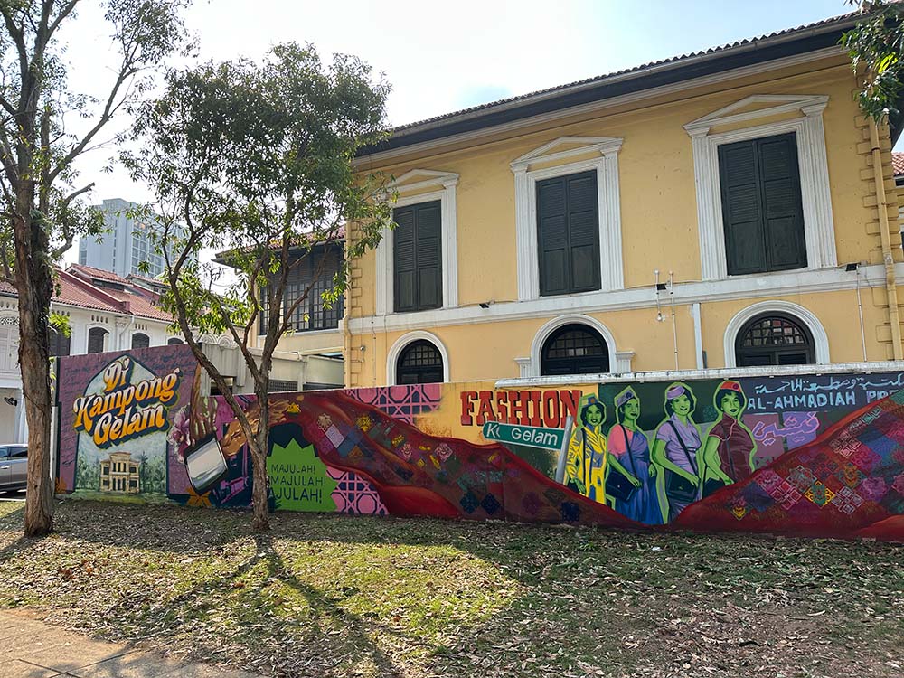 Colourful wall mural on low wall in front of a yellow building