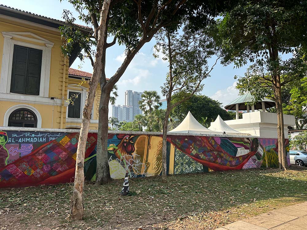 Colourful wall mural on low wall in front of a yellow building