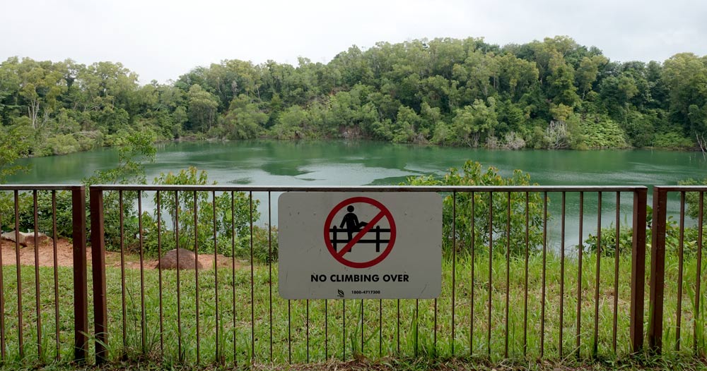 A fence and a warning sign for people not to climb over.