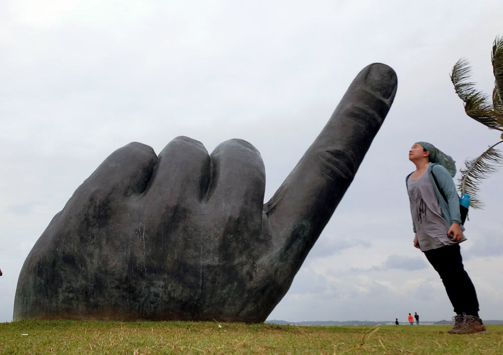 A giant hand sculpture is way taller than me at Changi Point Park