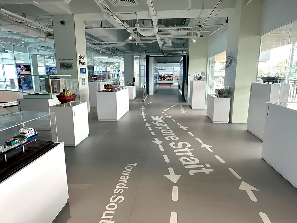 A large hall with exhibits and a floor sticker with the words 'Singapore strait'