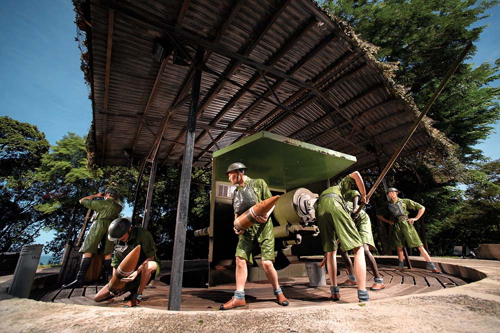 WWII diorama of soldiers in green uniforms loading artillery into a cannon